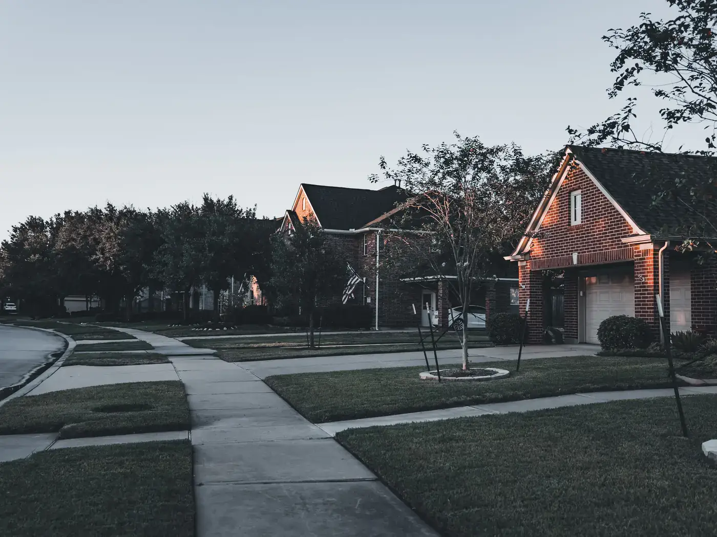 Suburban street with brick family homes and lawns at dusk