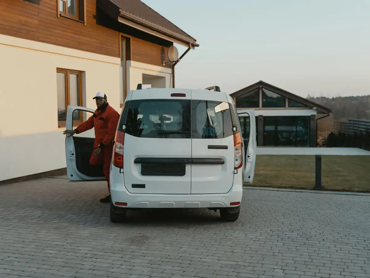 Worker stepping out of a white work van parked in a home's driveway
