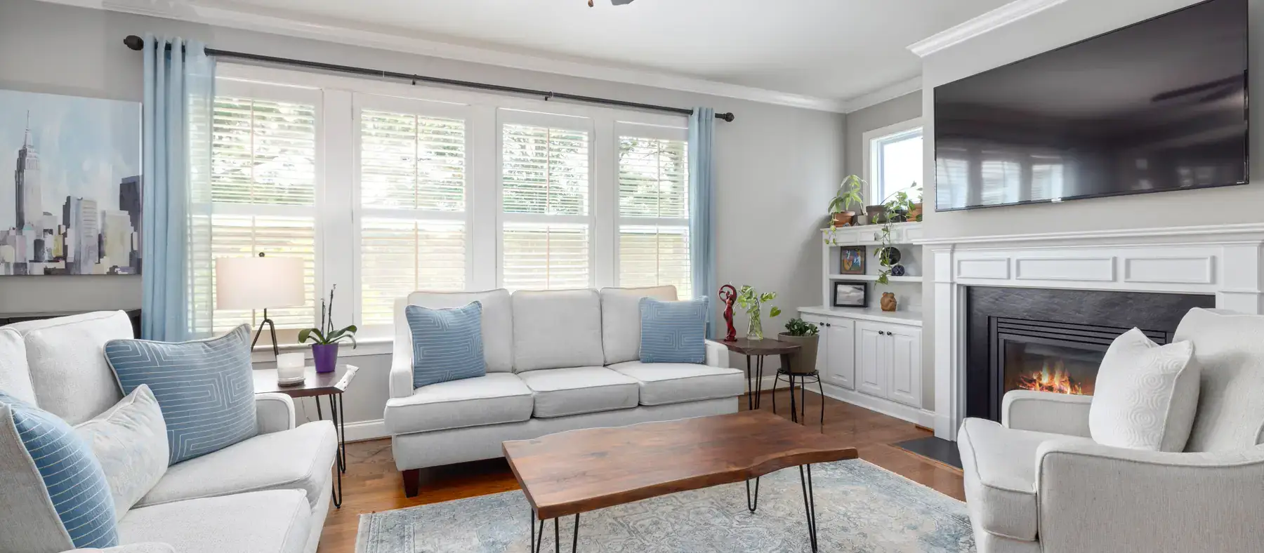 Bright living room with white sofas, a fireplace and large windows
