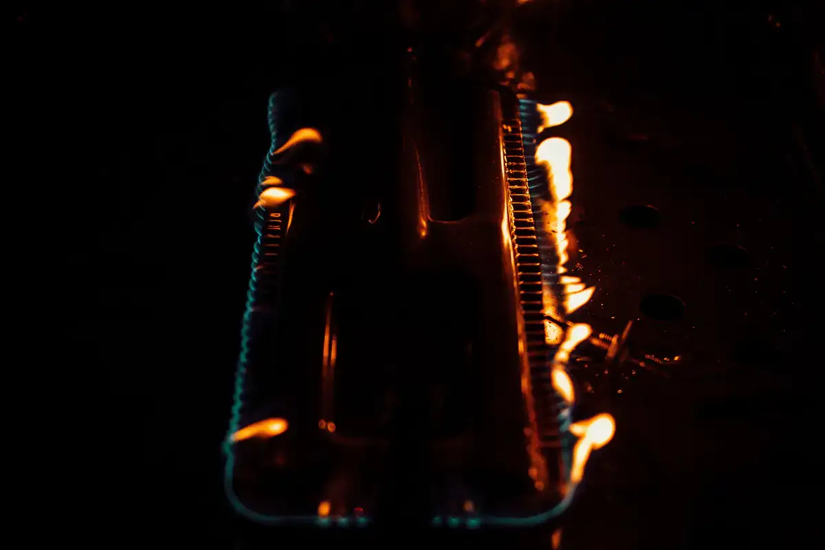 Orange gas flames along a pair of burner tubes in a dark cabinet