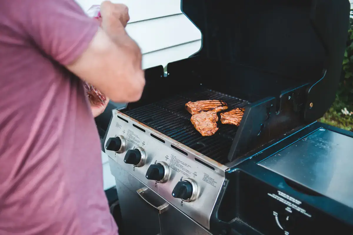 Steaks cooking on an outdoor gas grill with the lid open