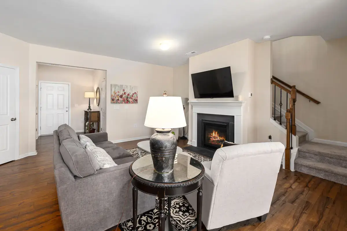 Living room with gray sofas and a lit gas fireplace below a mounted TV