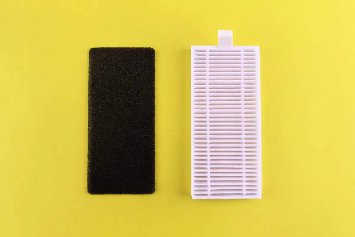 Black foam filter and white pleated air filter side by side on a yellow background